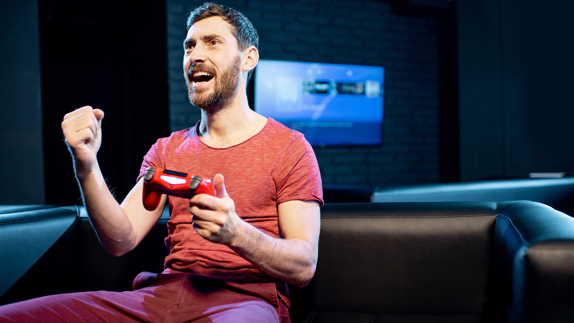 Happy man playing video games with gaming console in the club